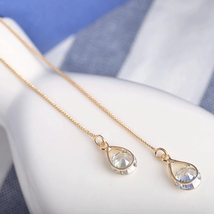 Boucles d'oreilles pendantes dorées avec gouttes en zircon et longs glands sur céramique