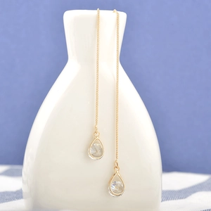 Détail de boucles d'oreilles pendantes dorées avec zircon goutte sur vase céramique