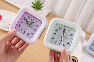 Detail of colorful purple and green square plastic alarm clocks held in hand