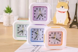 Detailed view of four colorful square quartz alarm clocks on a cozy wooden desk