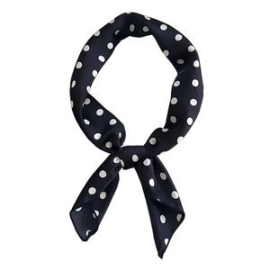 Classic black and white polka dot silk scarf tied in a stylish knot on white background