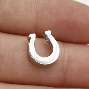 Close-up of a silver horseshoe-shaped stainless steel pendant held between fingers