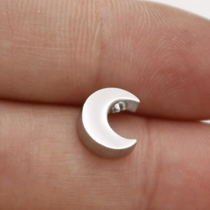 Detailed macro shot of silver stainless steel crescent moon jewelry pendant on finger