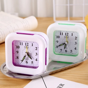 Minimalist square plastic quartz alarm clocks in purple and green on a silver tray