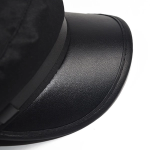 Close-up of black PU leather brim and textured fabric detail on a baker boy hat
