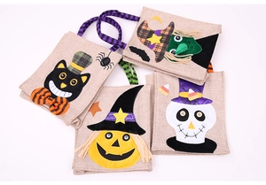 Detailed view of four linen Halloween candy bags with pumpkin, witch, cat, and skull designs