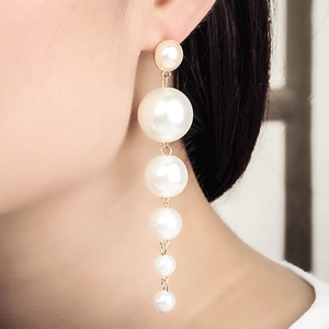 Detail of elegant long pearl drop earrings with gold links shown on a model