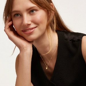 Close-up of minimalist gold-plated chain necklace with a delicate square lock pendant