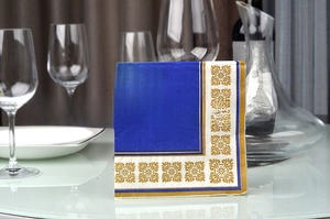 Close-up of blue napkins with gold floral patterns in a luxury dining table setting
