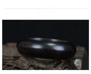 Close-up of dark rosewood ring with natural grain texture on a rustic wooden log