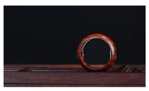 Detailed view of dark mahogany wood ring showing natural grain texture on a black background