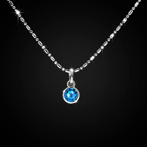Close-up of a blue birthstone crystal pendant on a silver beaded chain necklace