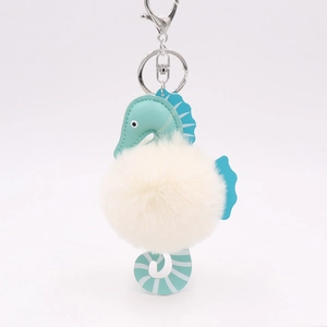 Close-up of cute teal seahorse keychain with soft beige pompom on a white background