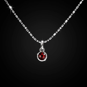 Close-up of a silver alloy necklace featuring a round red gemstone pendant on a black background