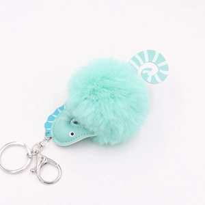 Detail of teal plush seahorse keychain with soft faux fur ball and silver metal hardware