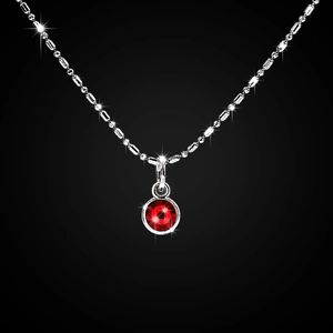 Macro view of silver bead chain and a sparkling deep red gemstone pendant on black background