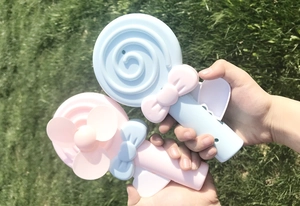 Close-up of blue and pink lollipop-shaped manual hand-pressure fans for kids outdoors