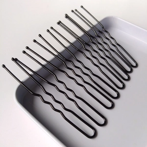 Vue détaillée d'épingles à cheveux en métal noir en forme de U sur un plateau gris