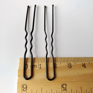 Détail d'épingles à cheveux en U en métal noir avec règle mesurant environ 6 cm