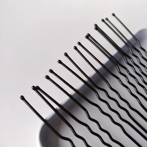 Gros plan d'épingles à cheveux en métal noir en forme de U avec des bouts ronds de protection