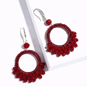 Handwoven deep red hoop earrings with bohemian beadwork on minimalist white surface