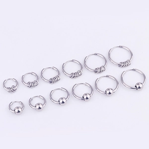 Macro detail of silver stainless steel hoop earrings in various sizes on purple background