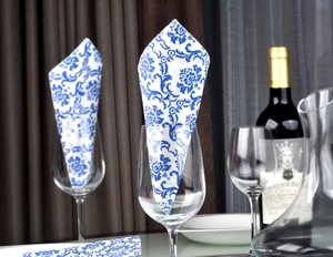 Blue and white floral paper napkins folded in elegant glasses for table decoration
