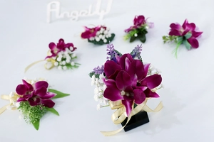 Detalle del boutonnière de orquídea púrpura con lazo de satén y flores blancas decorativas