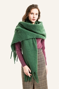Detalle de bufanda de felpa verde con borlas gruesas usada por una modelo de moda