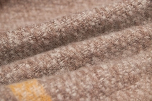 Macro shot of thick fringe scarf showing brown and beige knit texture and wool blend fabric