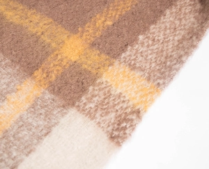 Close-up of soft thick plaid fabric in brown and yellow tones showing cozy mohair texture