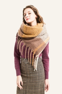 Macro detail of thick brown and beige plaid scarf showing soft wool-like fringe texture