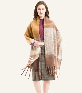 Close-up of thick checkered mohair shawl with tassels in earth tones on a white background