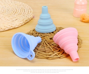 Close-up of foldable silicone kitchen funnels in blue and pink on a wooden desk