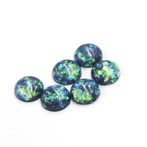 Detailed macro view of 12mm round blue synthetic opal resin stones with green foil effects