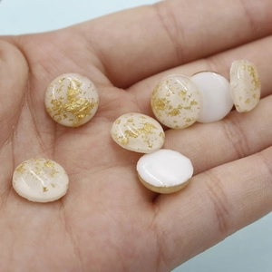 Macro shot of 12mm oval resin opal cabochons with gold foil flakes for jewelry making