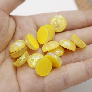 Detailed view of 12mm yellow synthetic opal resin cabochons with glitter foil effect