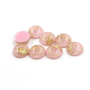 Close-up of pink oval resin cabochons with gold foil inclusions for jewelry making