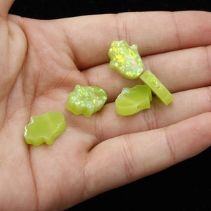 Close-up of translucent yellow-green Hamsa Hand resin beads with rainbow glitter flakes