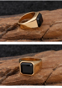 Macro detail of men's vintage gold ring with large square black stone on wood
