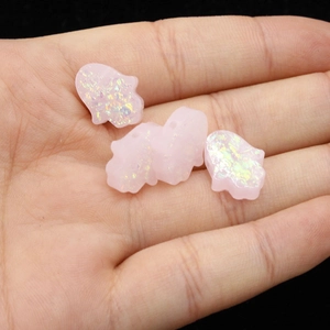 Detailed view of four pink glitter resin Hamsa Hand pendants held in a palm for DIY jewelry
