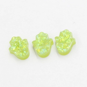 Detailed macro view of three yellow-green resin Hamsa hand beads with sparkling texture