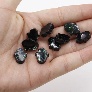 Close-up of eight black glitter resin Hamsa hand beads for DIY jewelry making
