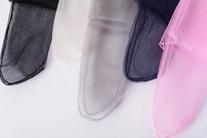 Flat lay of transparent mesh socks in black, beige, gray, navy, and pink on white background