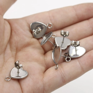 Detailed view of silver stainless steel heart earring studs with hanging loops on palm