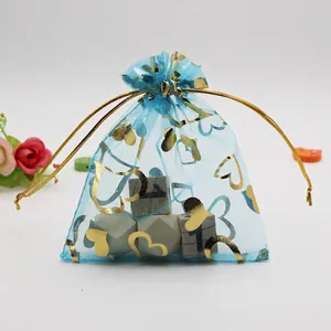 Detailed view of a blue organza jewelry pouch with gold heart prints and a silk drawstring