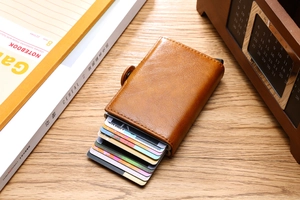 Macro shot of brown PU leather card holder with automatic aluminum ejection mechanism on wood