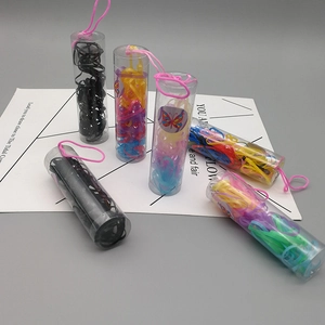 Detail view of colorful and black hair elastics in a clear cylinder with pink handle