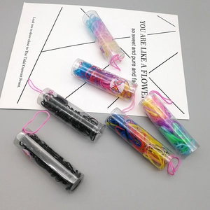 Close-up of black and colorful disposable rubber hair bands in clear cylindrical tubs