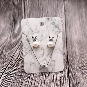 Creative rabbit pendant necklace and pearl earrings set on white marble display card